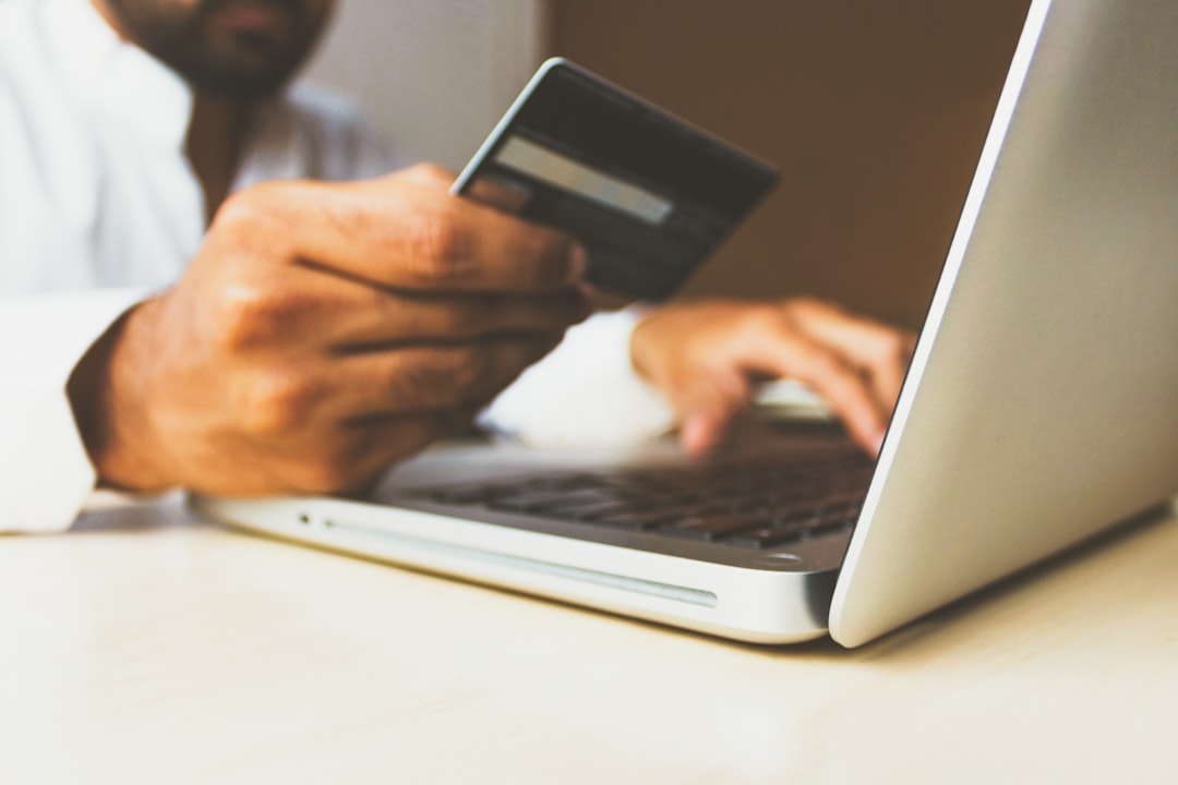 Personne effectuant un achat en ligne sur un ordinateur portable avec une carte bancaire